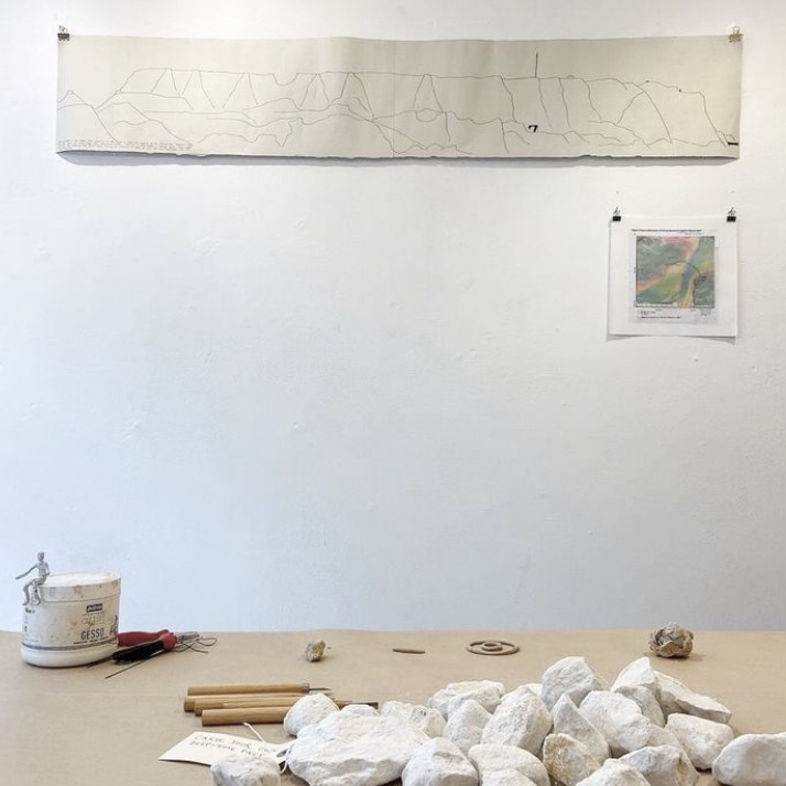Large pieces of irregular shaped white chalk and carving materials sat on a wooden table.